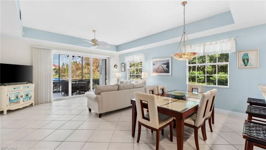 Dining space featuring ceiling fan, a raised ceiling, and light tile patterned floors