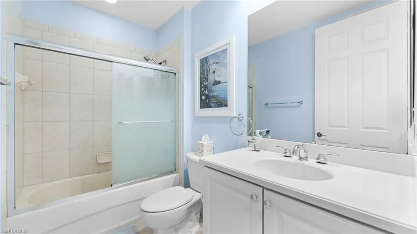 Full bathroom with shower / bath combination with glass door, vanity, and toilet