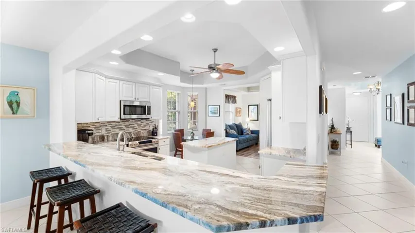 Kitchen featuring kitchen peninsula, backsplash, white cabinets, and ceiling fan