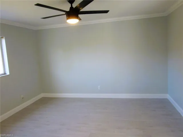 Empty room featuring ornamental molding, light wood finished floors, and ceiling fan