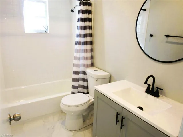 Full bathroom with vanity, shower / tub combo, and light marble finish flooring