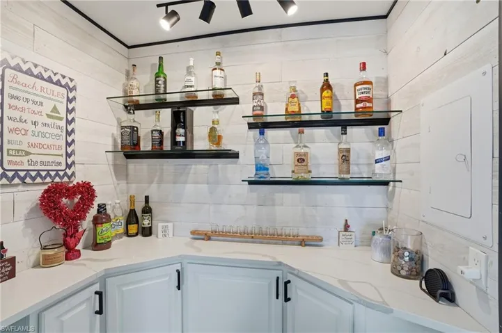 Kitchen featuring open shelves, light stone countertops, electric panel, and white cabinets