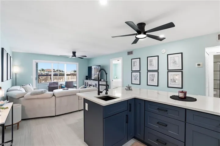Kitchen with light quartz countertops, open floor plan, a ceiling fan, and blue cabinets