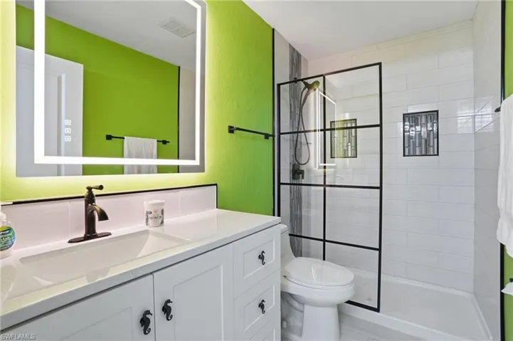 Bathroom with vanity, a textured wall, and tiled shower