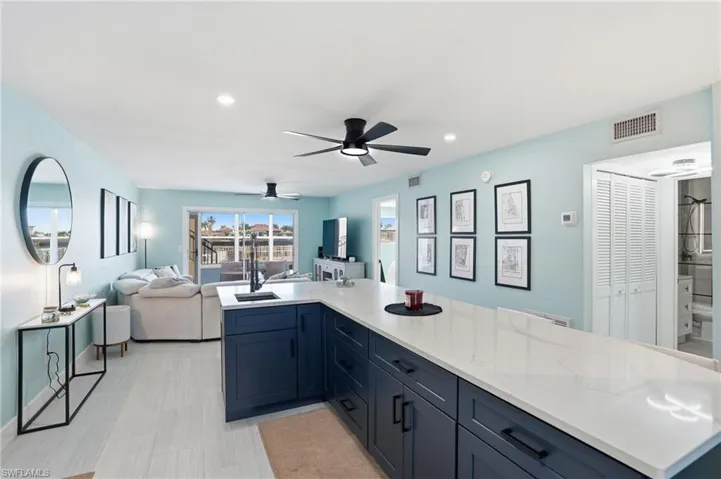Kitchen with open floor plan, blue cabinets, recessed lighting, ceiling fan, and light quartz counters