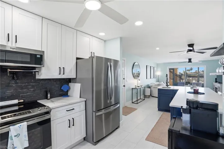 Kitchen with a ceiling fan, stainless steel appliances, open floor plan, white cabinets, and recessed lighting
