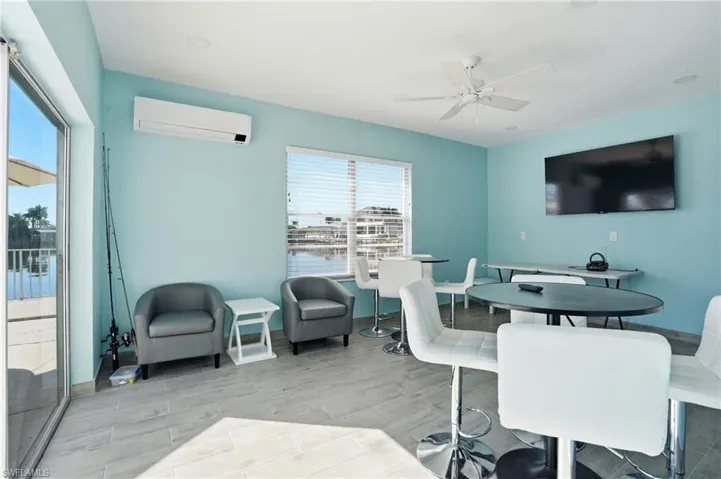 Clubhouse room off pool area featuring wood finish floors, a wall mounted mini split, and a ceiling fan