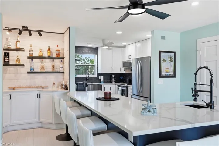 Kitchen featuring white cabinetry, a breakfast bar, stainless steel appliances, open shelves, and recessed lighting