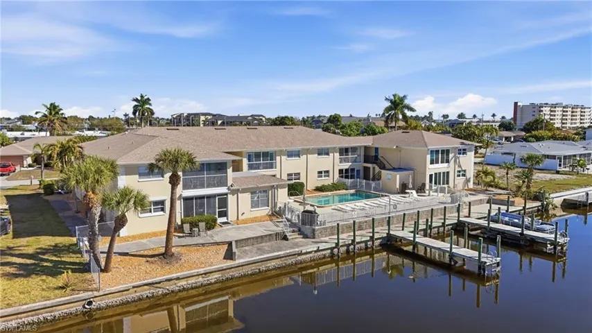 Rear view of property with a community pool, a water view, a patio area, and stucco siding