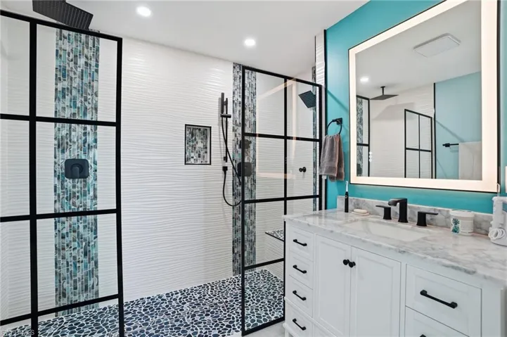 Bathroom featuring vanity, a walk in shower, and recessed lighting