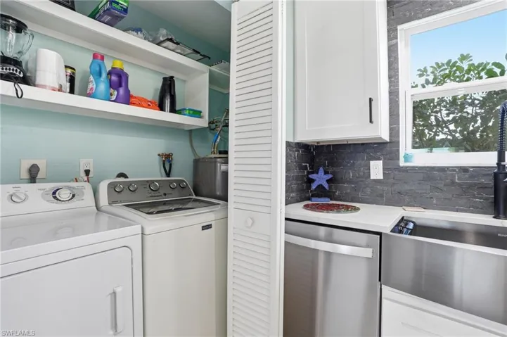 Laundry area featuring washing machine and dryer, water heater, and healthy amount of natural light