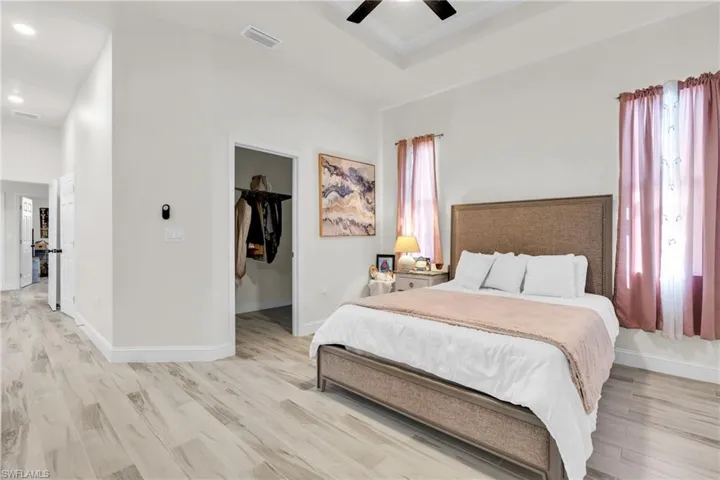 Bedroom featuring a spacious closet, light wood-style floors, ceiling fan, baseboards, and visible vents