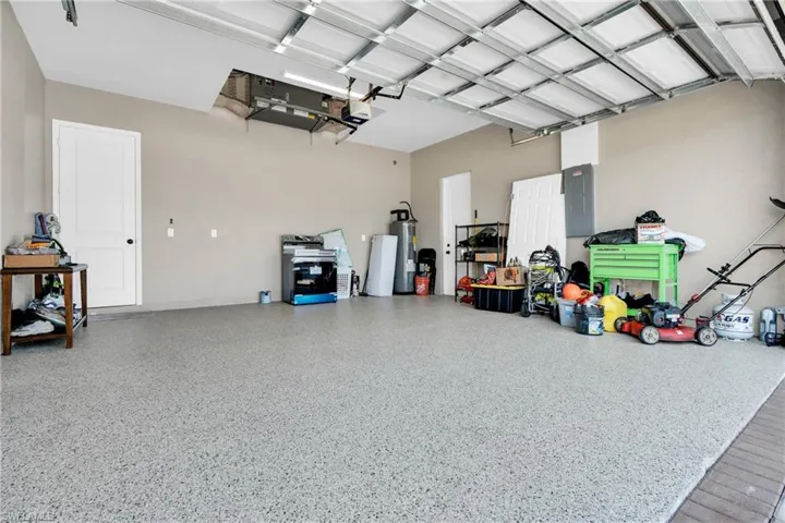 Garage with water heater, electric panel, and a garage door opener
