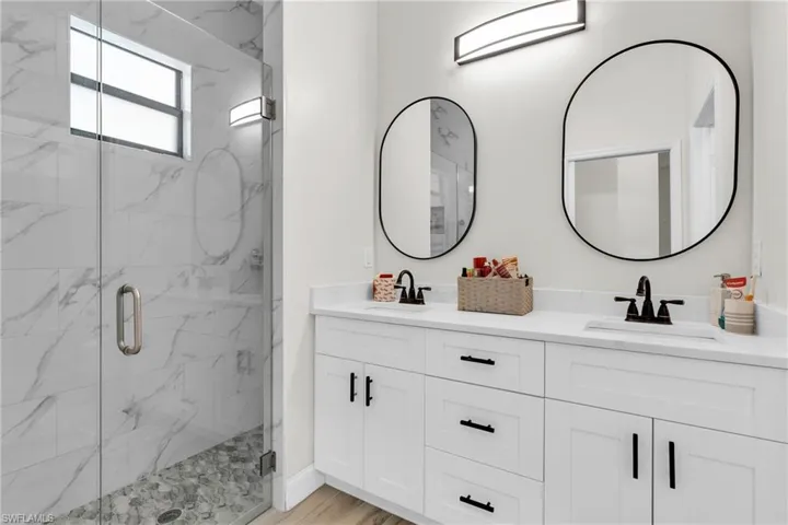 Bathroom featuring a sink, a marble finish shower, and double vanity