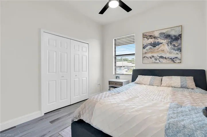 Bedroom featuring ceiling fan, baseboards, wood finished floors, and a closet