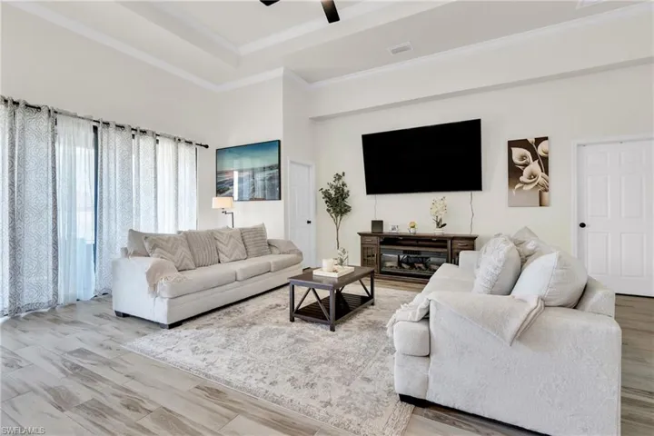 Living area featuring wood finished floors, visible vents, ornamental molding, and ceiling fan