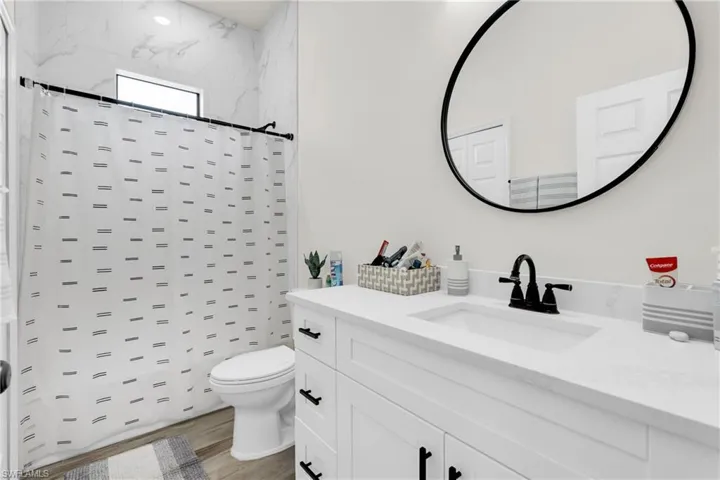 Full bathroom featuring curtained shower, wood finished floors, toilet, and vanity