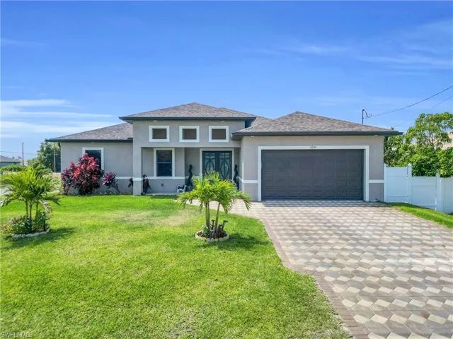 Prairie-style home featuring fence, a garage, stucco siding, a front yard, and decorative driveway