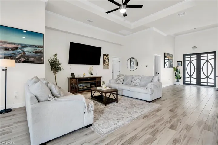 Living area featuring a ceiling fan, light wood-type flooring, french doors, ornamental molding, and visible vents