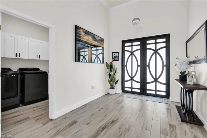 Foyer entrance with washing machine and dryer, baseboards, crown molding, and light wood-style floors