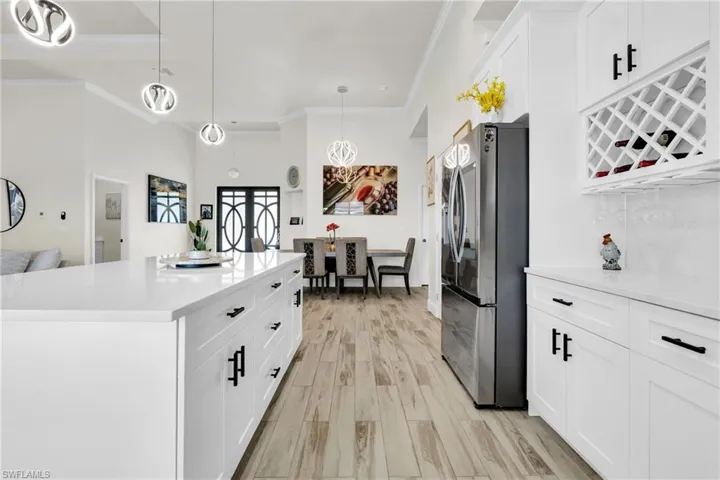 Kitchen featuring white cabinets, light countertops, freestanding refrigerator, and ornamental molding