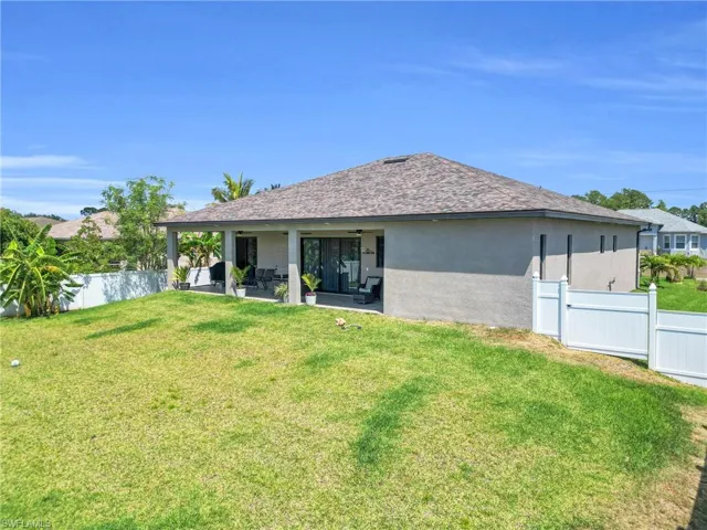 Back of property featuring stucco siding, a yard, and fence