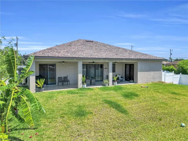 Back of house featuring ceiling fan, a patio, a yard, and stucco siding