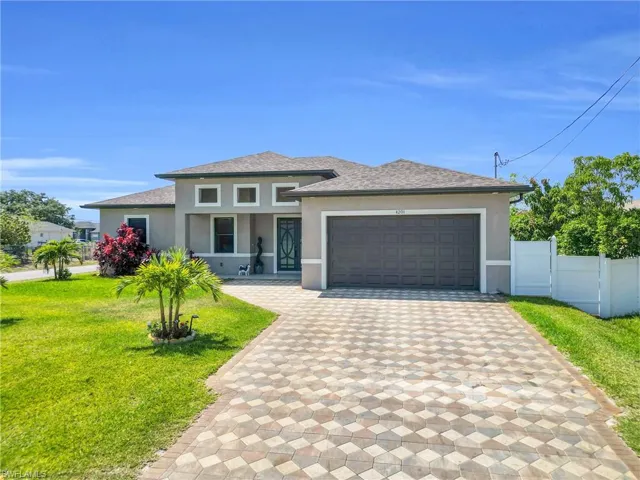 Prairie-style home featuring decorative driveway, a front lawn, an attached garage, fence, and stucco siding