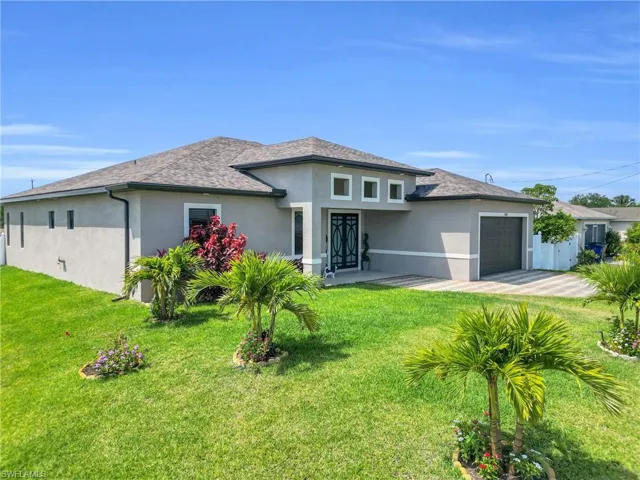 Rear view of property featuring a garage, a yard, roof with shingles, and stucco siding
