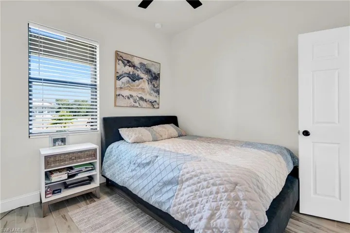 Bedroom with wood finished floors, a ceiling fan, and baseboards