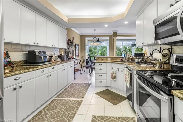 Kitchen featuring stainless steel appliances, sink, white cabinetry, and light tile flooring