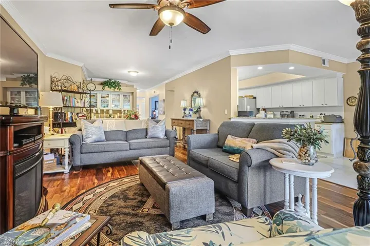 Living room featuring ceiling fan, hardwood / wood-style flooring, and crown molding