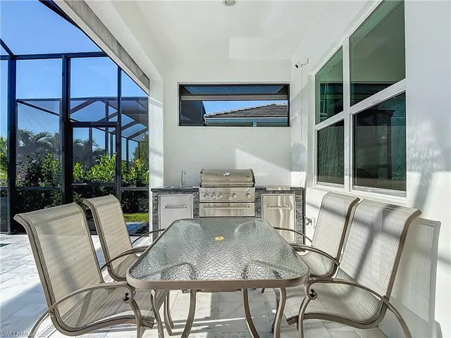 Kitchen featuring dark brown cabinets, decorative backsplash, a kitchen breakfast bar, pendant lighting, and light stone countertops