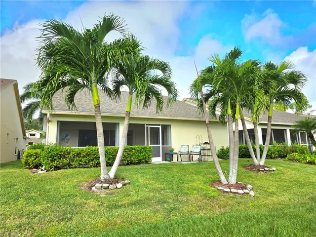Rear view of property with a sunroom, stucco siding, and lawn