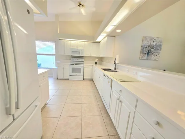 Kitchen with white appliances, white cabinets, light countertops, light tile patterned floors, and a ceiling fan