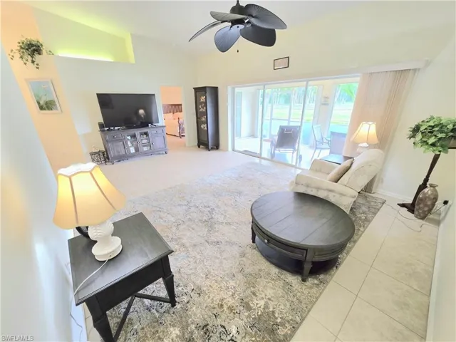 Living room featuring light tile patterned flooring, ceiling fan, and high vaulted ceiling
