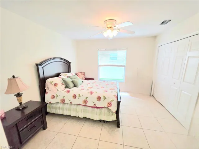 Bedroom with light tile patterned flooring, ceiling fan, and a closet