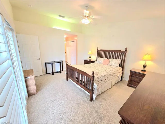 Bedroom with light carpet, a closet, and a ceiling fan