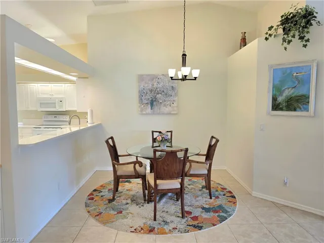 Dining area with light tile patterned floors, high vaulted ceiling, and a chandelier