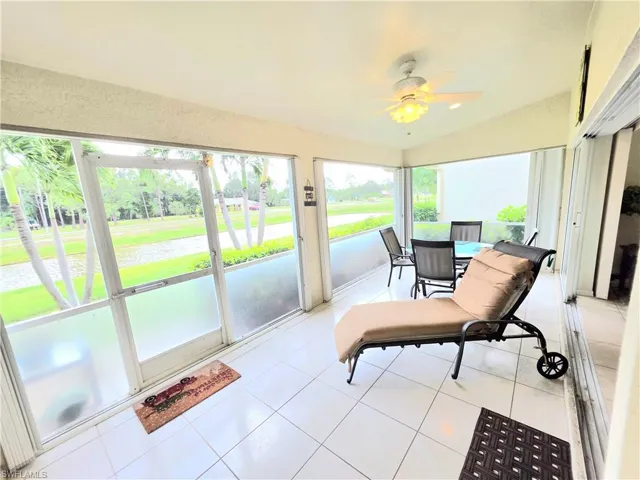 Sunroom featuring tile patterned floors, a water view, ceiling fan, and vaulted ceiling