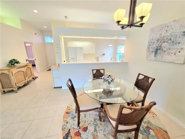 Dining room with a chandelier, light tile patterned flooring, and recessed lighting