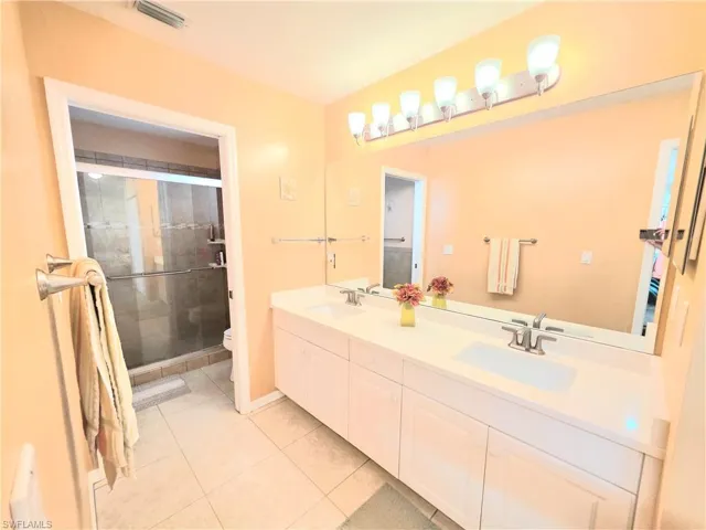 Bathroom featuring double vanity, a shower stall, and light tile patterned floors