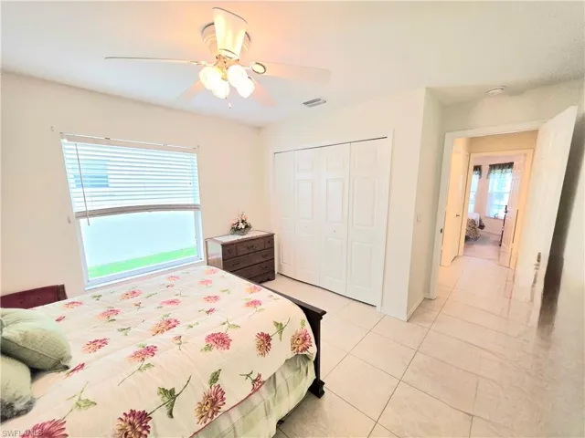 Bedroom with light tile patterned flooring, a ceiling fan, and a closet