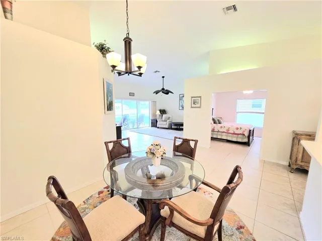 Dining room with light tile patterned flooring, a chandelier, and a high ceiling