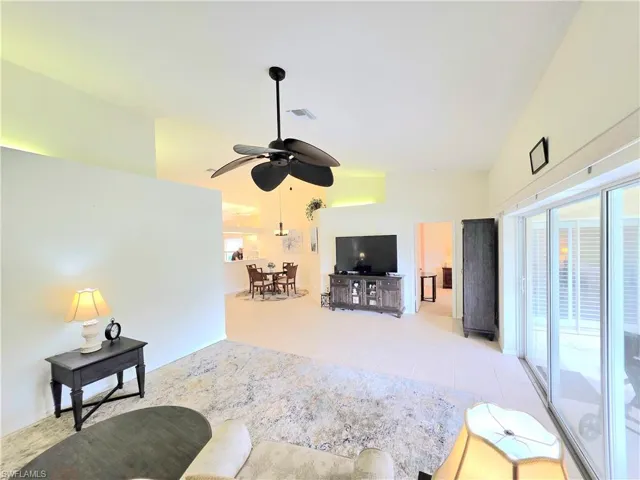Living room featuring healthy amount of natural light, a ceiling fan, high vaulted ceiling, and light tile patterned flooring