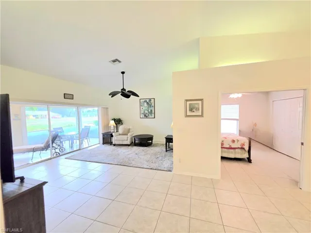Living area featuring light tile patterned floors, lofted ceiling, and a ceiling fan