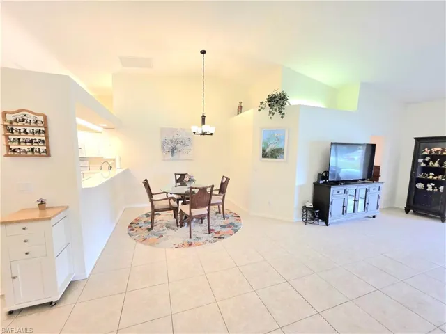 Dining space with light tile patterned flooring, a chandelier, and vaulted ceiling