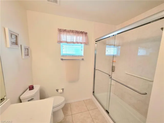 Full bath with light tile patterned flooring, a shower stall, and vanity