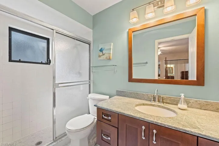 Bathroom featuring ceiling fan, an enclosed shower, vanity, and toilet