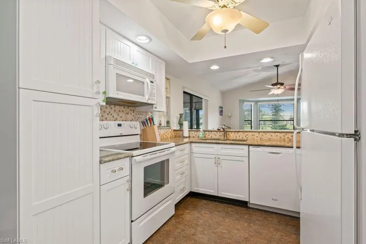 Kitchen featuring ceiling fan, sink, white appliances, and white cabinets